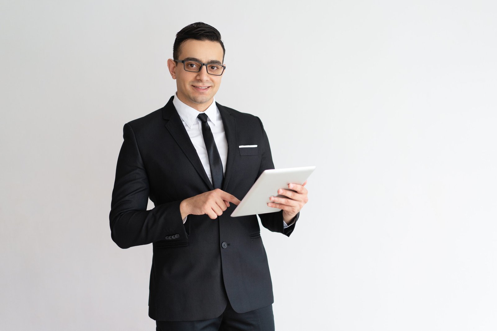 Cheerful young businessman checking email on tablet and looking at camera. Positive successful entrepreneur using gadget as personal organizer. Technology concept
