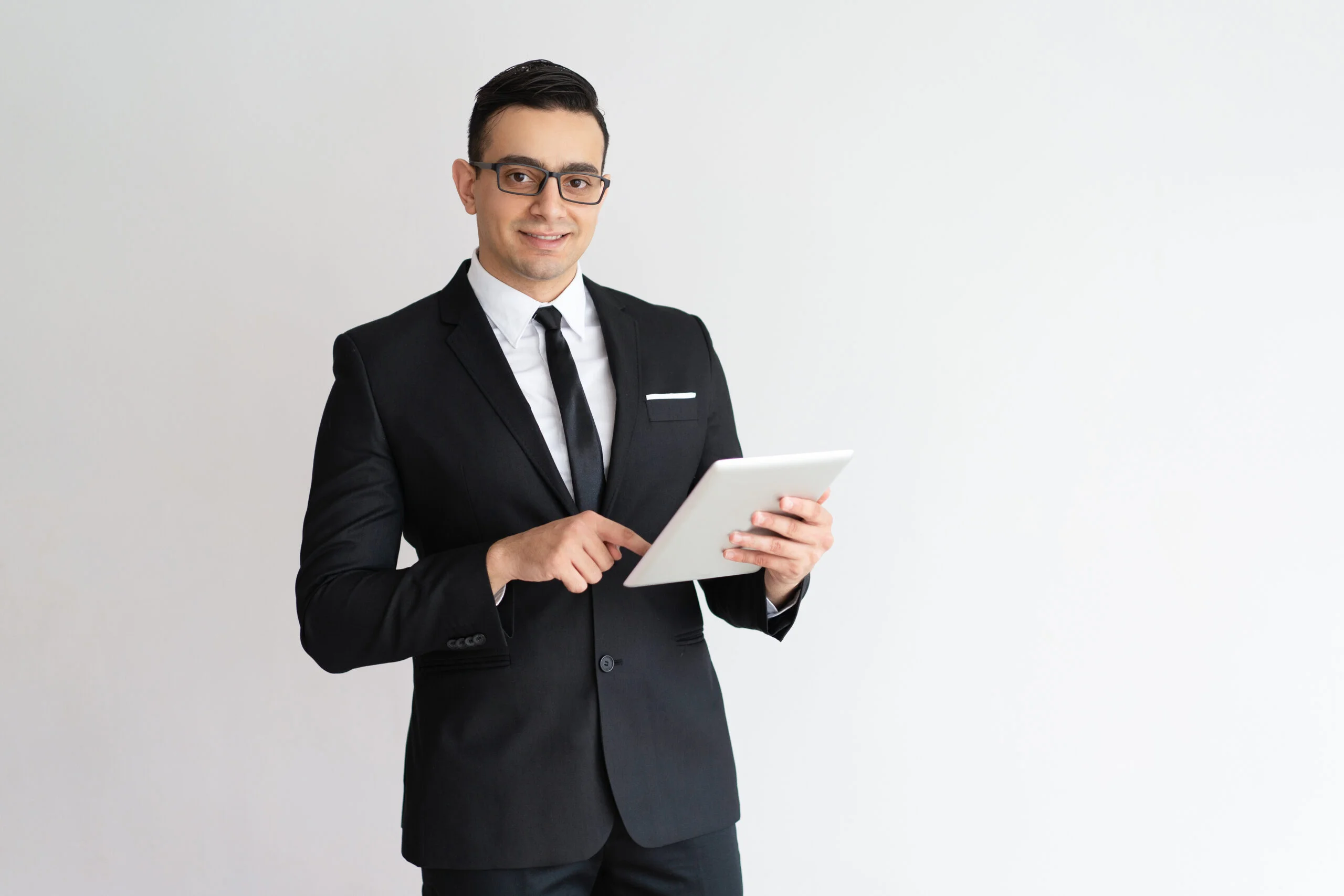 Cheerful young businessman checking email on tablet and looking at camera. Positive successful entrepreneur using gadget as personal organizer. Technology concept